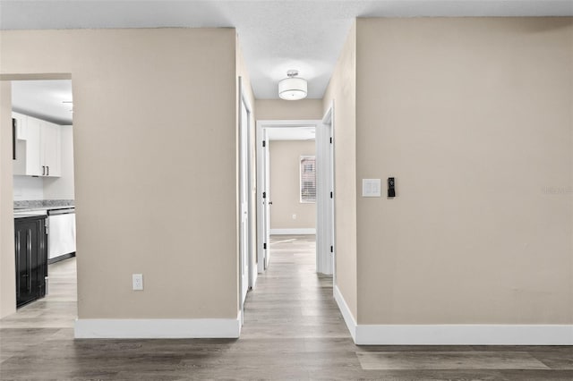 hallway with a textured ceiling and light wood-type flooring