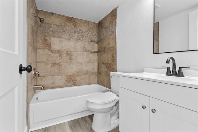 full bathroom featuring wood-type flooring, toilet, tiled shower / bath combo, and vanity