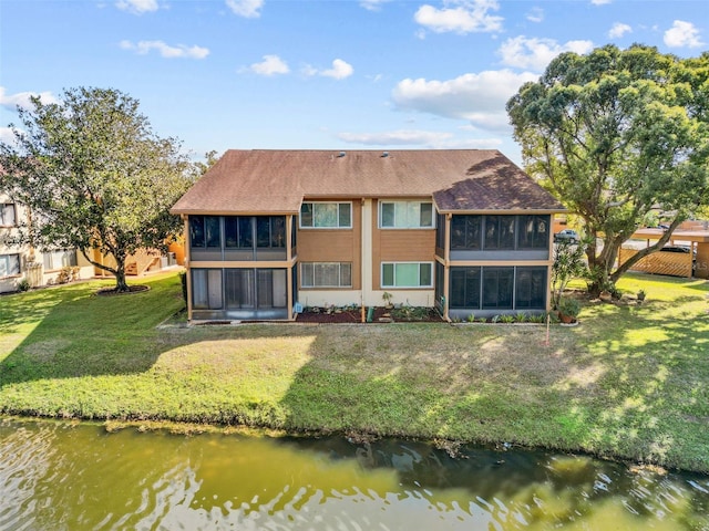 rear view of property featuring a yard, a sunroom, and a water view