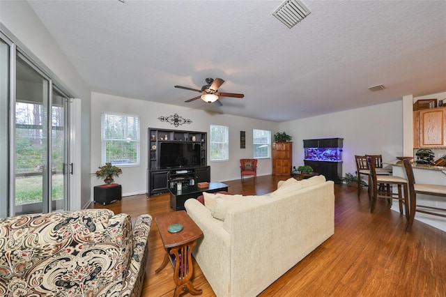 living room featuring a textured ceiling, ceiling fan, and dark hardwood / wood-style flooring