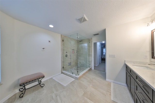 bathroom featuring walk in shower, vanity, and a textured ceiling