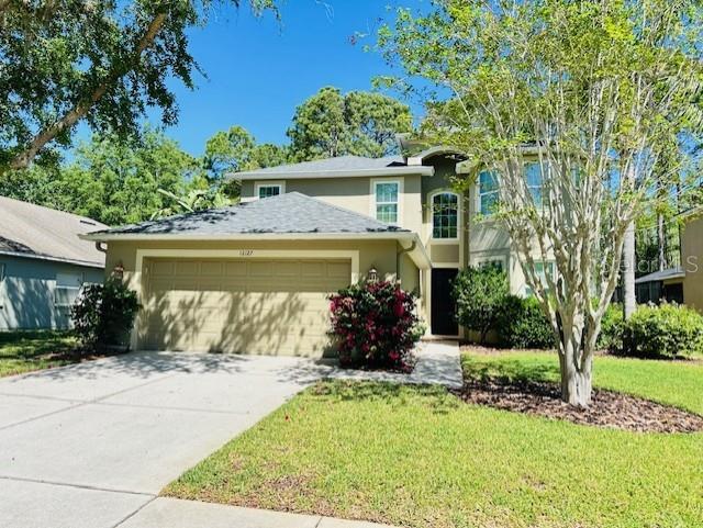 12127 Luftburrow Ln, Hudson, FL 34669 - view of front of house featuring a front lawn, driveway, stucco siding, and a garage