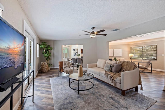 living room with ceiling fan, a textured ceiling, and dark hardwood / wood-style floors