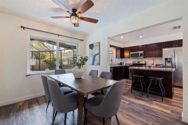 dining space with sink, ceiling fan, dark hardwood / wood-style floors, and a textured ceiling