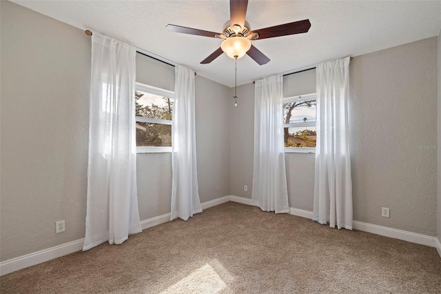 carpeted spare room featuring plenty of natural light and ceiling fan