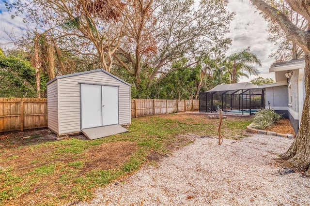 view of yard with glass enclosure, a fenced in pool, and a storage unit