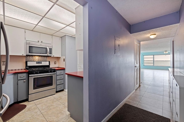 kitchen featuring ceiling fan, white cabinetry, backsplash, stainless steel appliances, and light tile patterned flooring