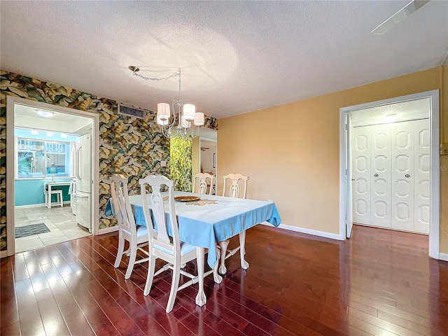 dining room with hardwood / wood-style floors, a textured ceiling, and an inviting chandelier