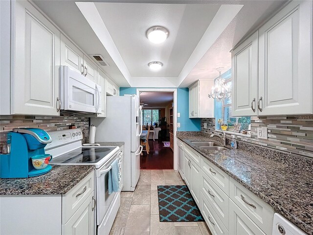 kitchen featuring sink, white appliances, white cabinets, and hanging light fixtures