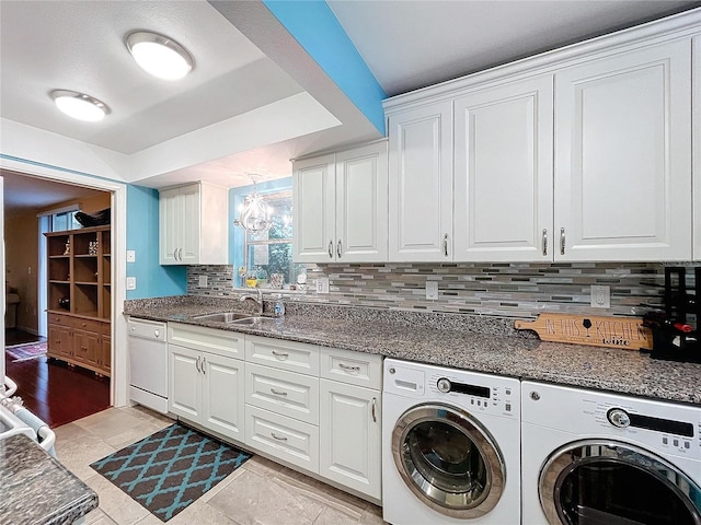 washroom with sink, a notable chandelier, independent washer and dryer, and cabinets