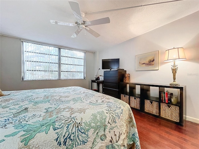 bedroom with ceiling fan, vaulted ceiling, dark wood-type flooring, and a textured ceiling