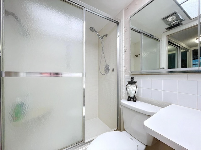 bathroom featuring a shower with shower door, tile walls, toilet, and tasteful backsplash