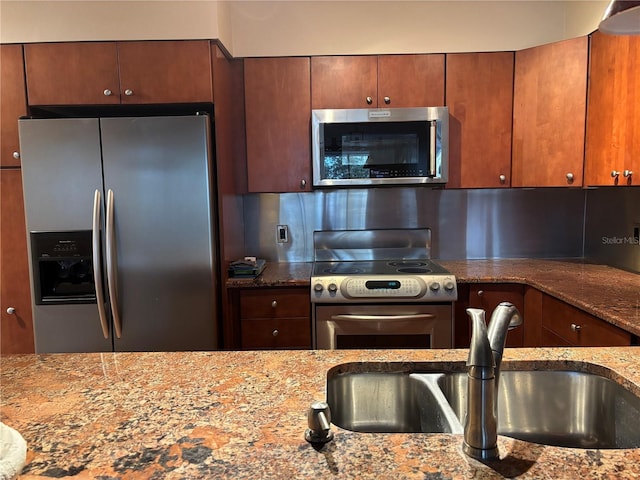 kitchen featuring stainless steel appliances, tasteful backsplash, sink, and stone counters