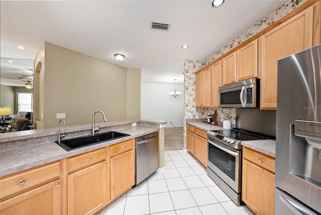 kitchen with stainless steel appliances, sink, a textured ceiling, and light tile patterned floors