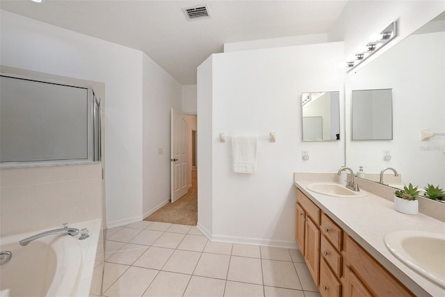 bathroom with vanity, a relaxing tiled tub, and tile patterned floors