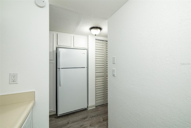 kitchen featuring white cabinets, dark hardwood / wood-style floors, white fridge, and a textured ceiling