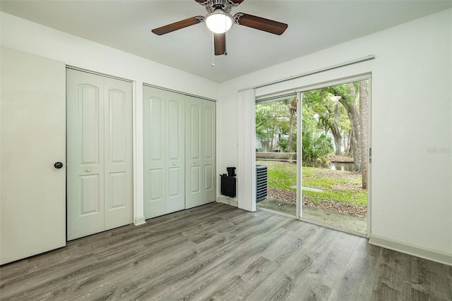 unfurnished bedroom featuring ceiling fan, light hardwood / wood-style flooring, access to outside, and multiple closets