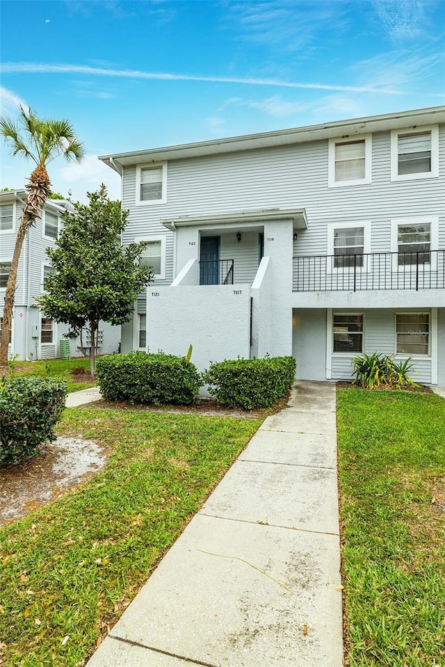 view of front of home featuring a front yard and a balcony