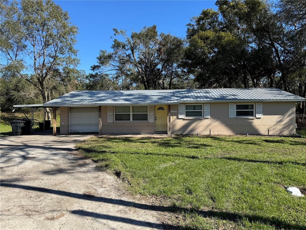 ranch-style house with a front lawn, a garage, and a carport