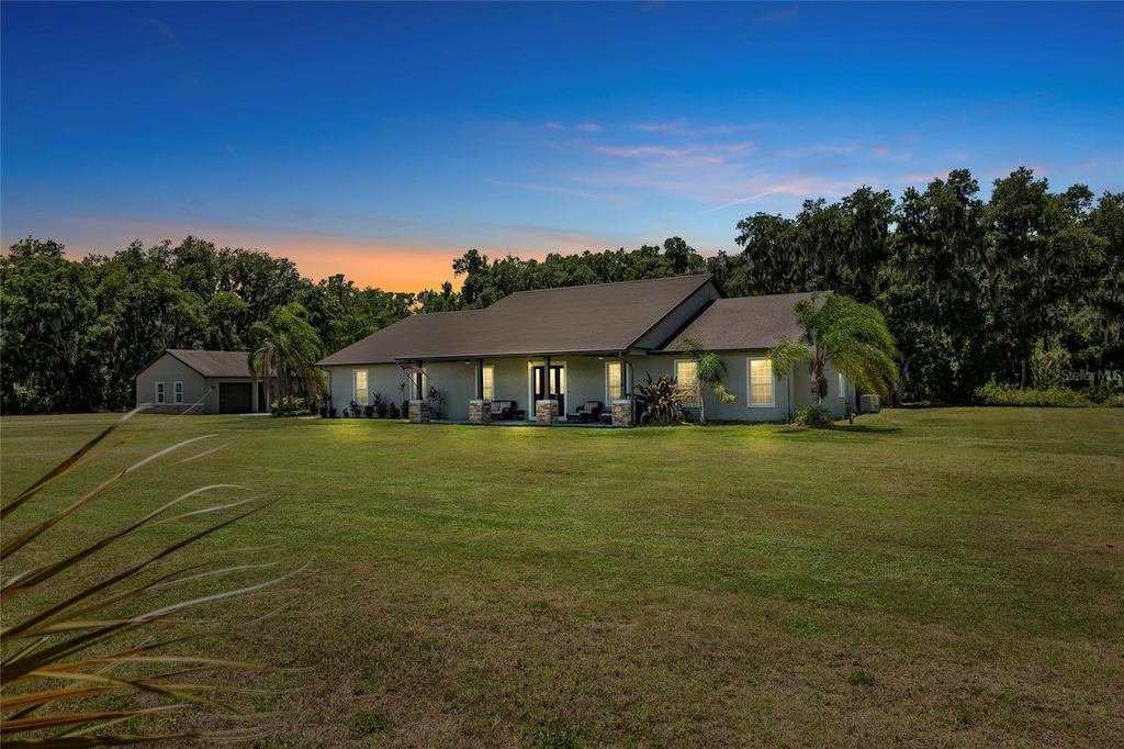 back house at dusk featuring a yard