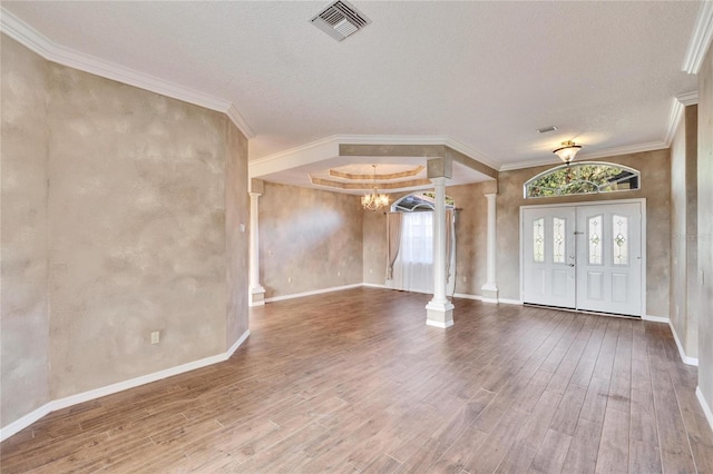 foyer entrance featuring decorative columns, wood-type flooring, a textured ceiling, and an inviting chandelier