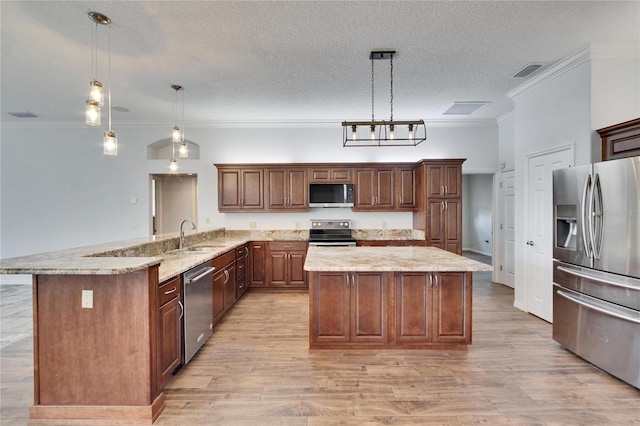 kitchen featuring a textured ceiling, appliances with stainless steel finishes, sink, hanging light fixtures, and kitchen peninsula