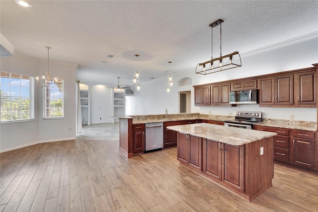 kitchen with a center island, crown molding, hanging light fixtures, kitchen peninsula, and stainless steel appliances