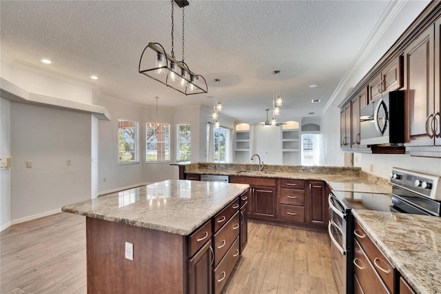 kitchen featuring pendant lighting, a textured ceiling, a kitchen island, stainless steel appliances, and sink