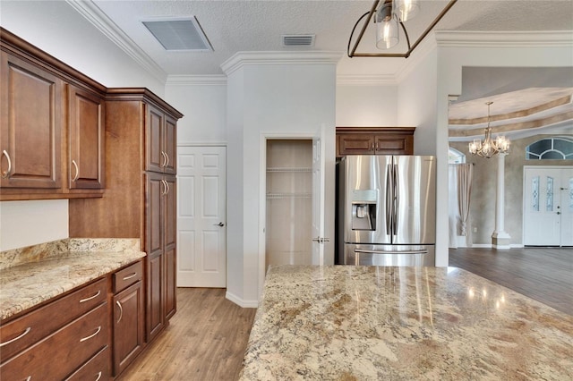 kitchen with light stone counters, a textured ceiling, stainless steel fridge, and ornamental molding