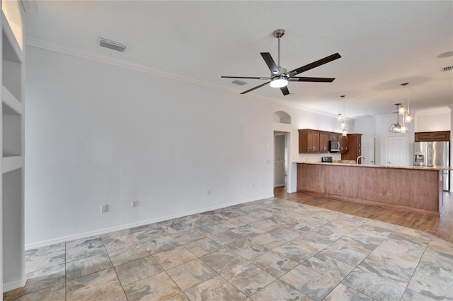 unfurnished living room with sink, ceiling fan, and ornamental molding