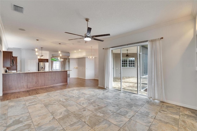 unfurnished living room featuring ceiling fan with notable chandelier, plenty of natural light, a textured ceiling, and ornamental molding