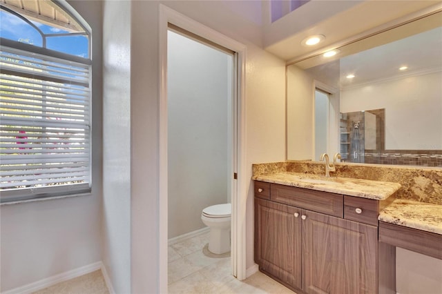 bathroom with a tile shower, toilet, a wealth of natural light, and vanity