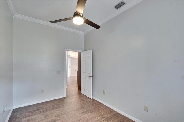 empty room featuring hardwood / wood-style flooring, crown molding, and ceiling fan