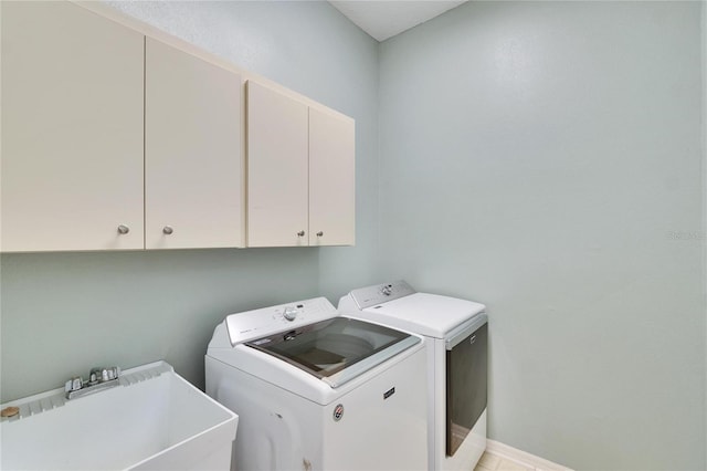 clothes washing area featuring sink, washing machine and dryer, and cabinets