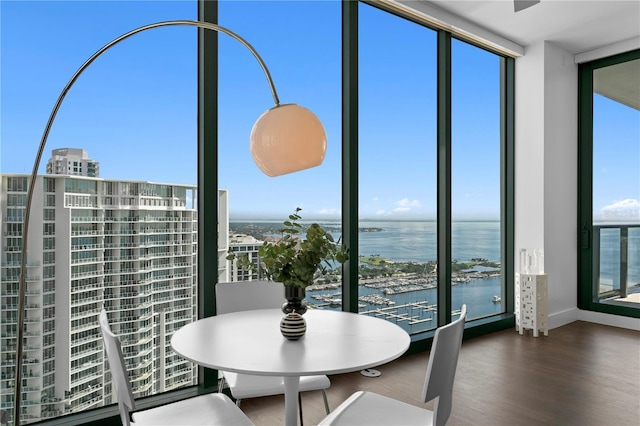 dining room featuring a water view, a wall of windows, and wood-type flooring