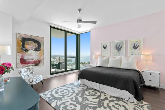 bedroom with ceiling fan, a water view, dark hardwood / wood-style floors, and floor to ceiling windows