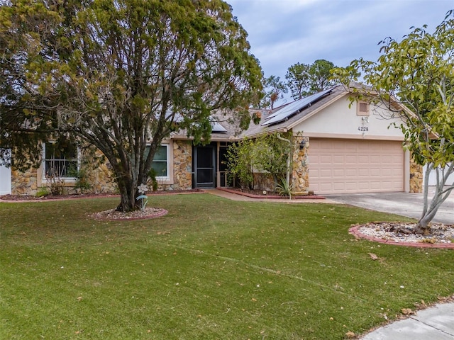 view of front of home with solar panels, concrete driveway, stone siding, an attached garage, and a front lawn