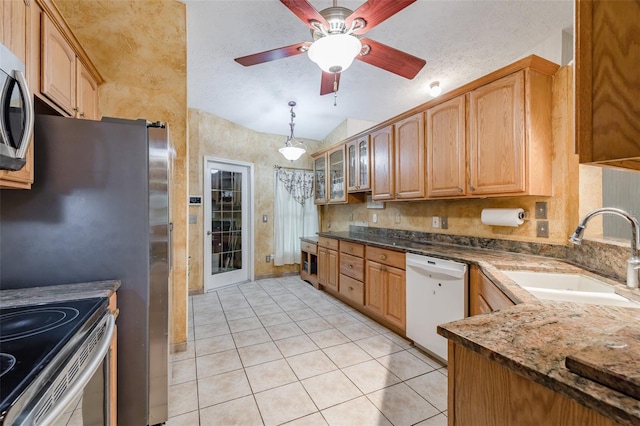 kitchen with lofted ceiling, sink, light tile patterned flooring, stainless steel appliances, and dark stone counters