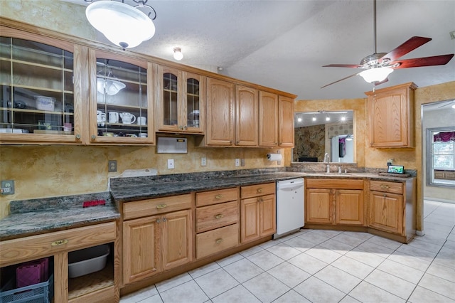 kitchen featuring dark stone countertops, sink, vaulted ceiling, white dishwasher, and light tile patterned floors