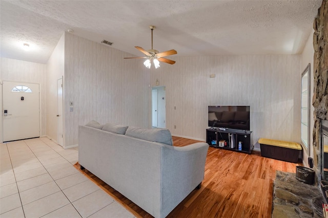 living room with ceiling fan, a textured ceiling, and lofted ceiling