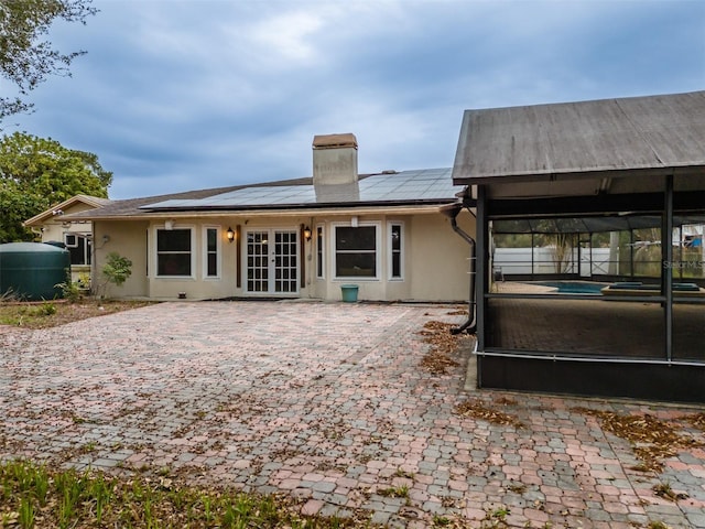 back of property featuring french doors and solar panels