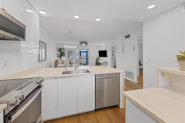 kitchen featuring light wood-type flooring, stainless steel appliances, white cabinets, and sink