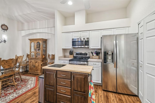 kitchen with white cabinets, wood counters, stainless steel appliances, tasteful backsplash, and dark brown cabinets