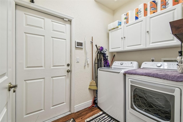 clothes washing area featuring dark wood-type flooring, cabinets, and washer and clothes dryer