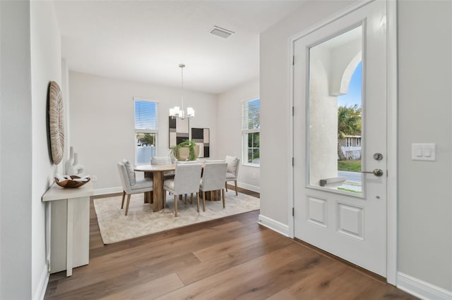 dining room featuring wood-type flooring and an inviting chandelier