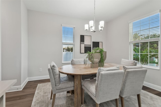 dining area with dark wood-type flooring and a notable chandelier