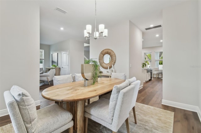 dining area featuring dark hardwood / wood-style floors and an inviting chandelier