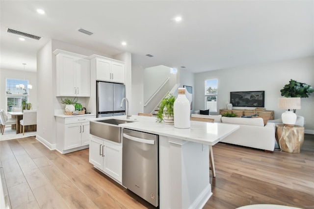 kitchen featuring white cabinets, appliances with stainless steel finishes, sink, and a center island with sink