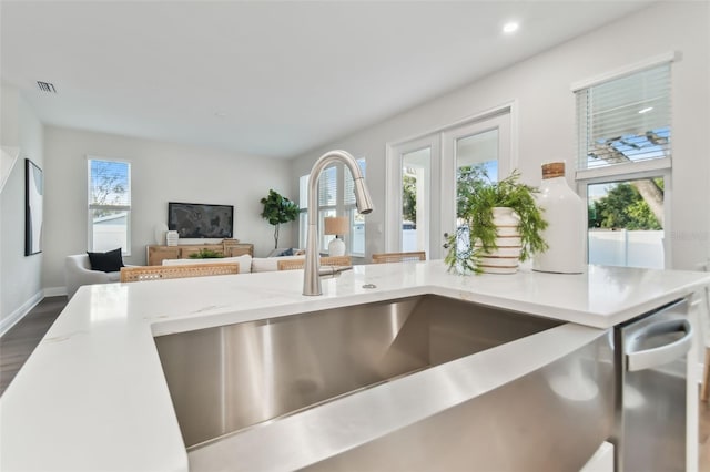 kitchen featuring light stone counters, sink, a wealth of natural light, and dark wood-type flooring