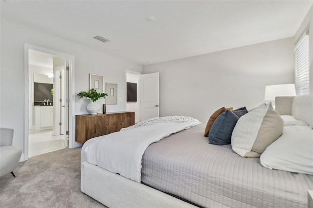 bedroom featuring light colored carpet and connected bathroom